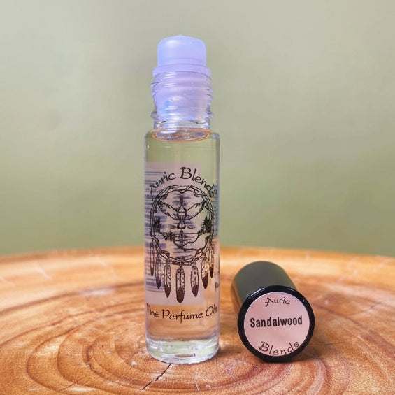 Auric Blends sandalwood perfume oil bottle on a wooden surface with a green background