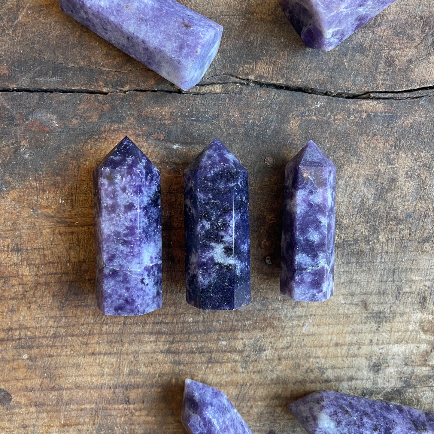 Purple and white charoite stones on a wooden surface