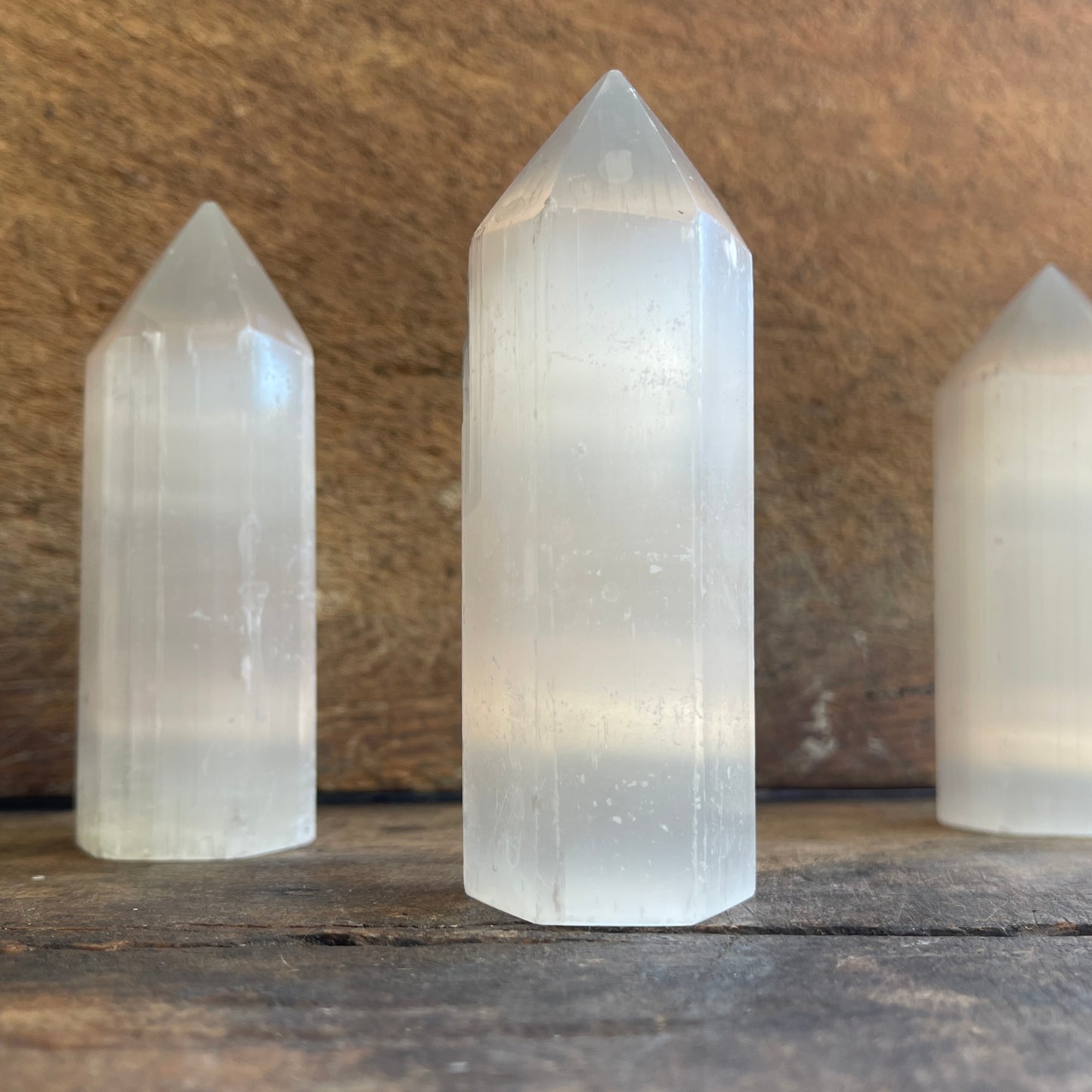 Three crystal towers on a wooden surface with a rustic background