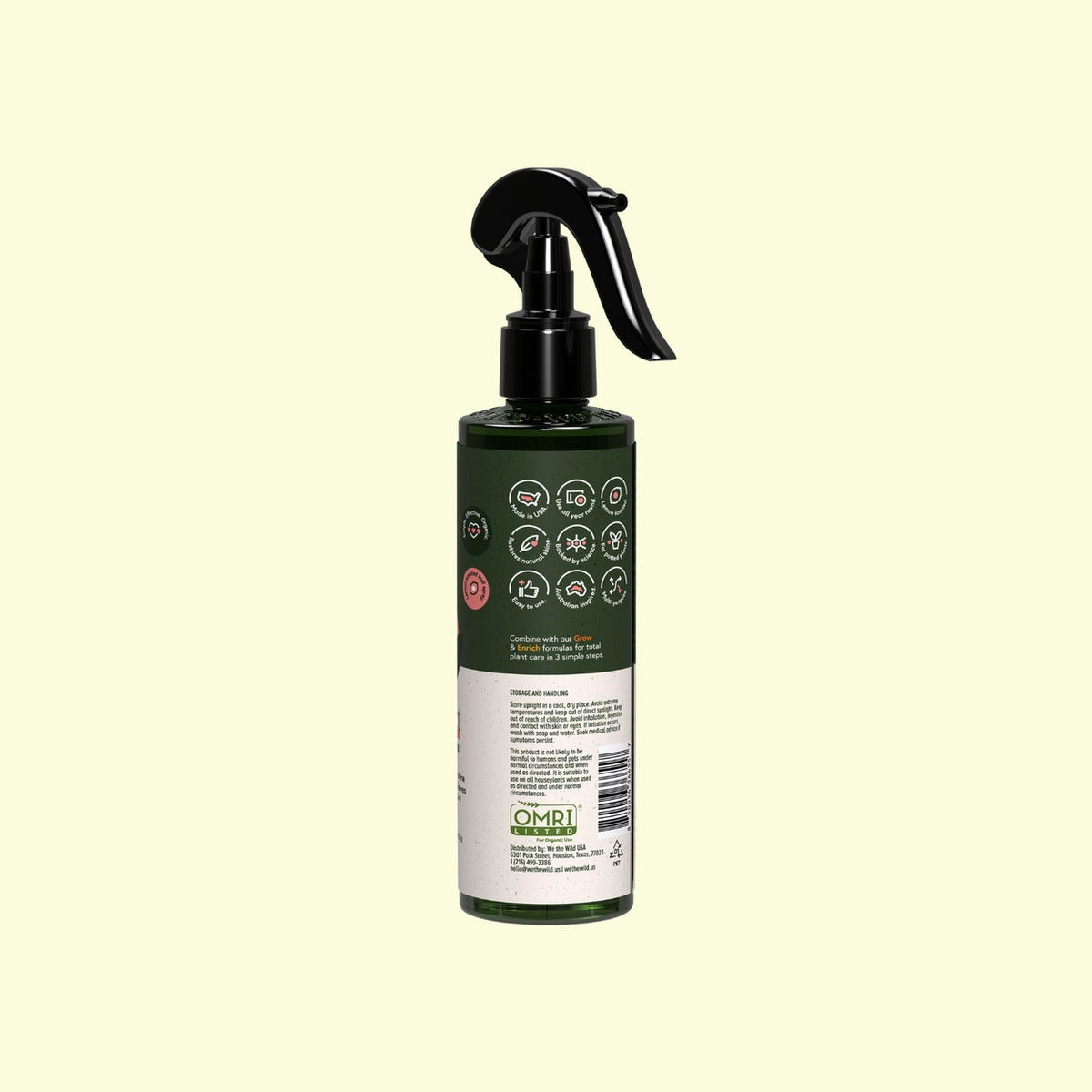 Green spray bottle with black nozzle on a beige background