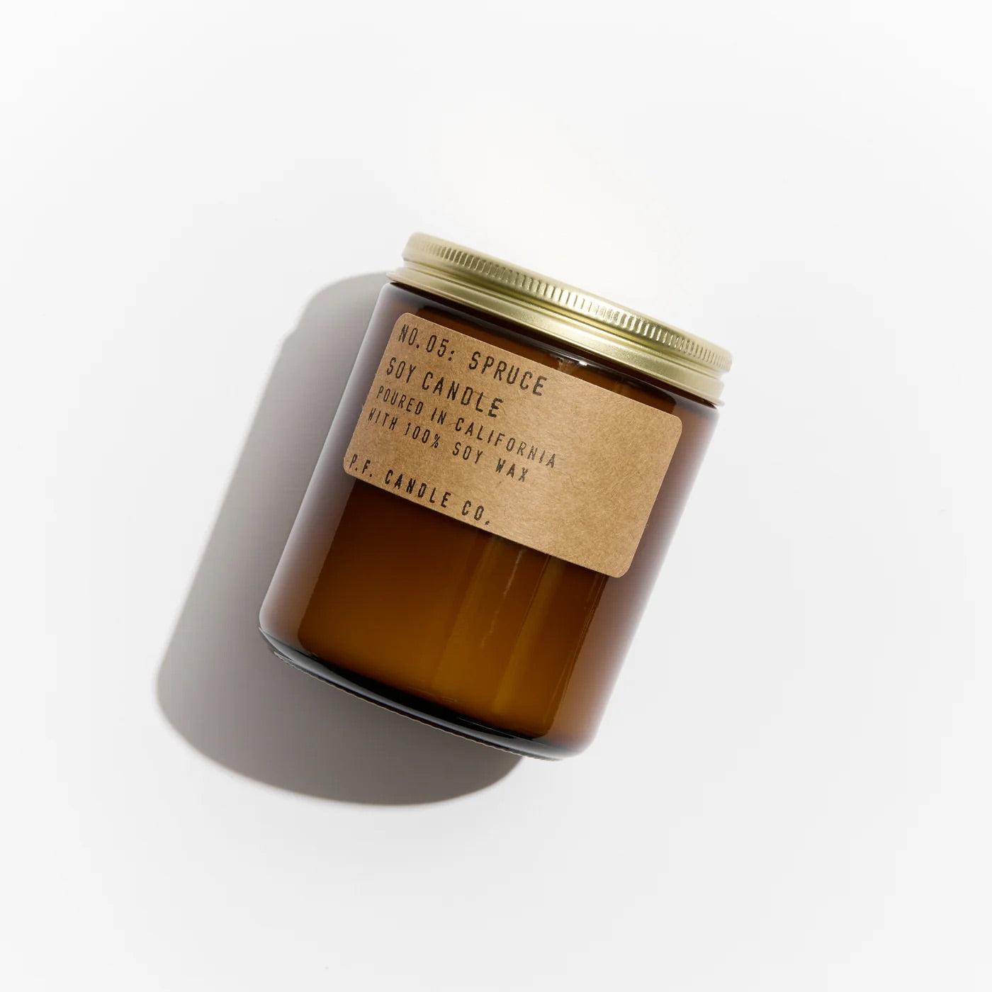 Amber glass candle with a gold lid and label on a white background