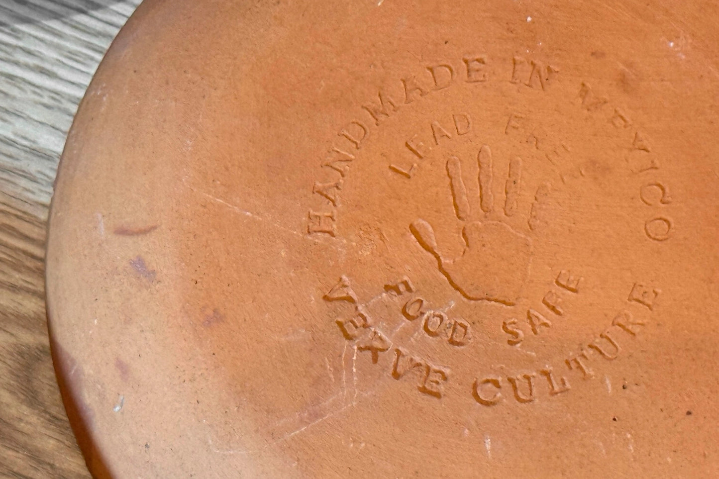 Terracotta dish with 'Handmade in New York' and 'Food Safe Live Culture' text on a wooden surface.