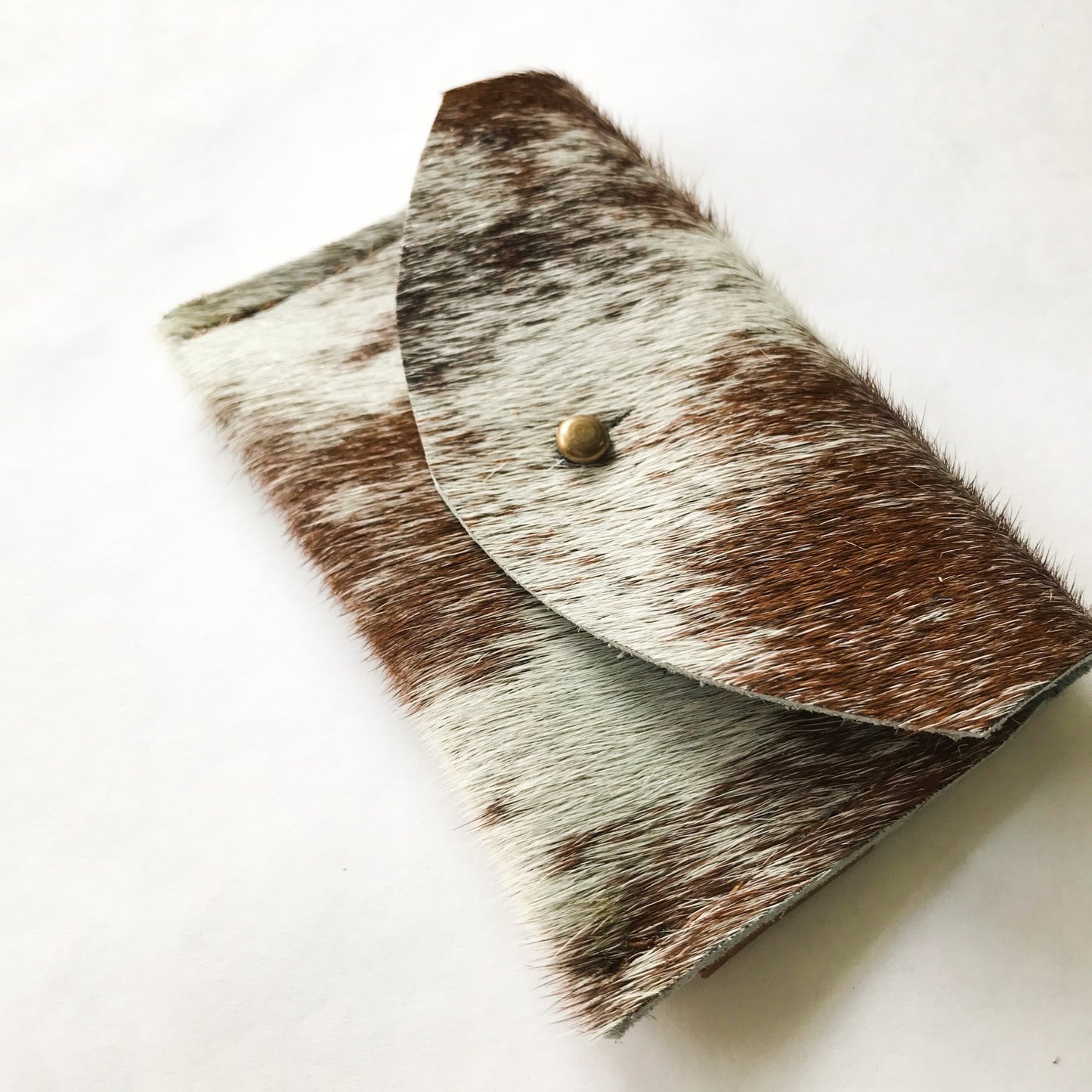 Cowhide wallet with a gold button on a white background