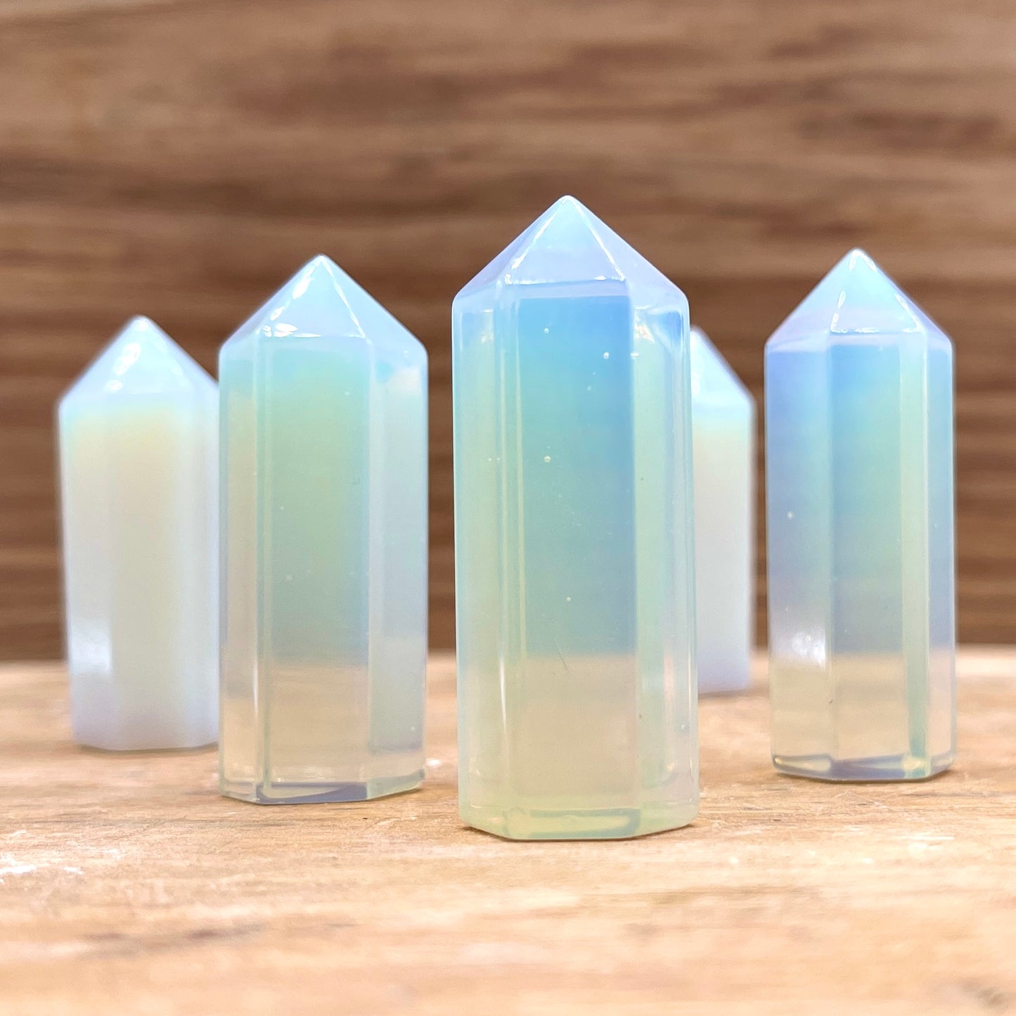 A collection of opalite points displayed on a wooden surface.