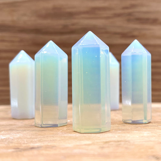 A collection of opalite points displayed on a wooden surface.