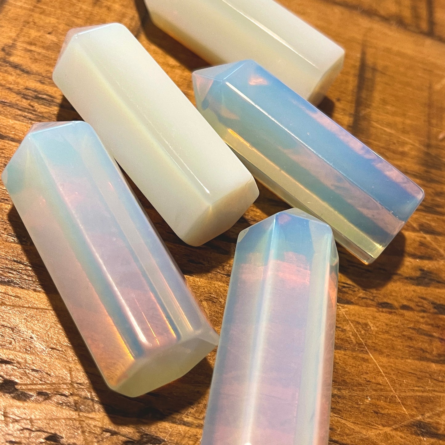 A collection of opalite points laid out on a wooden surface