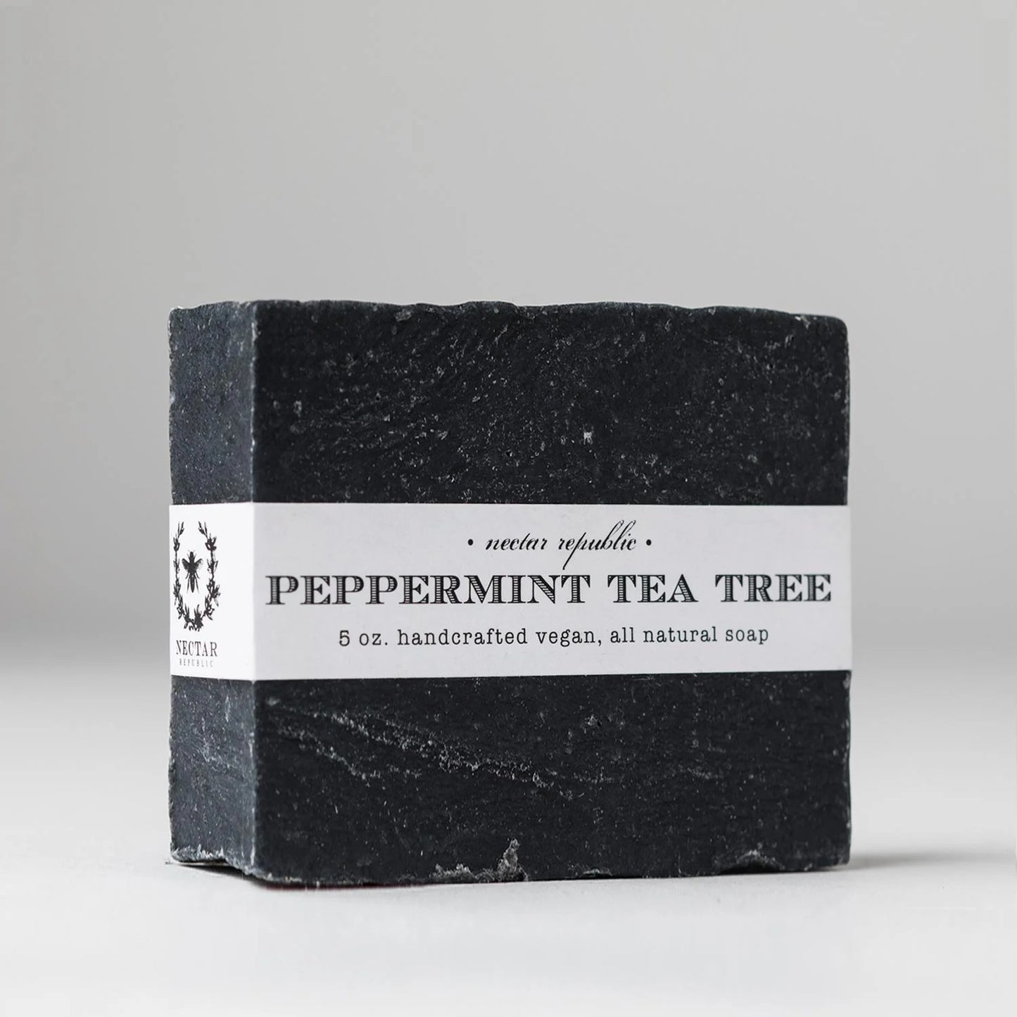 Black soap bar with a white label on a light gray background