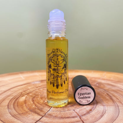 Roll-on bottle of Auric Blends Egyptian Goddess perfume on a wooden surface with a green background