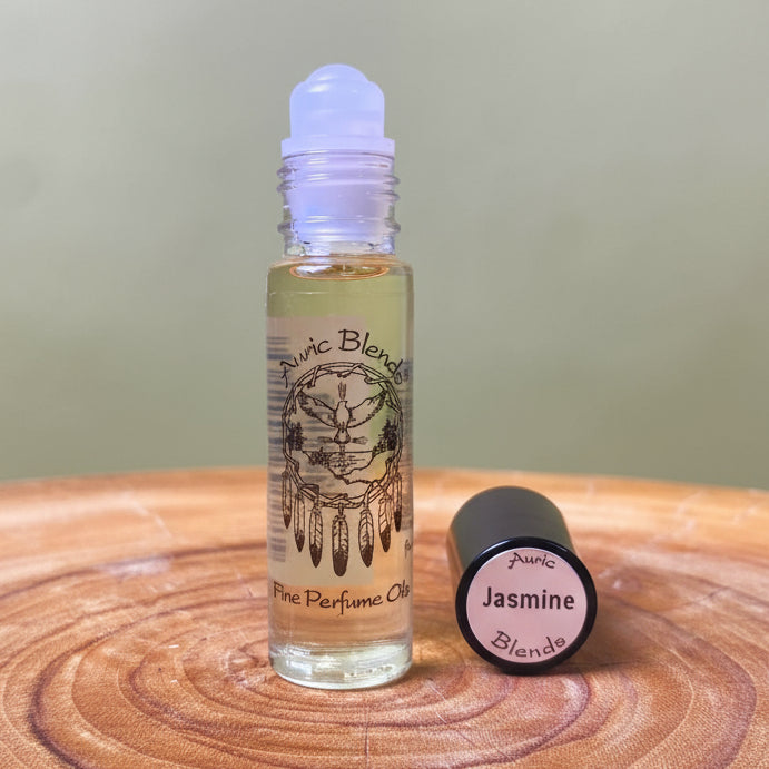 Roll-on bottle of Auric Blends Jasmine perfume on a wooden surface with a blurred green background