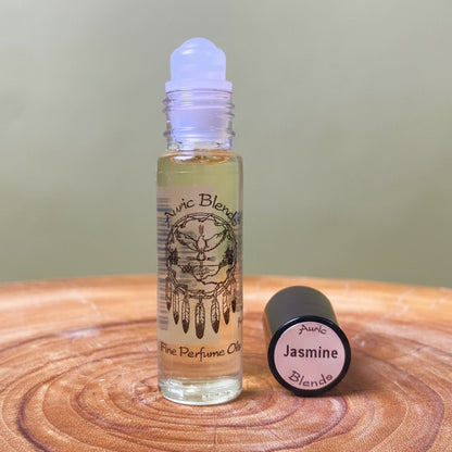 Roll-on bottle of Auric Blends Jasmine perfume on a wooden surface with a blurred green background