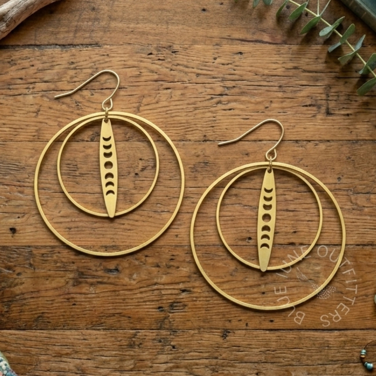 Gold hoop earrings with dangling elements on a wooden surface
