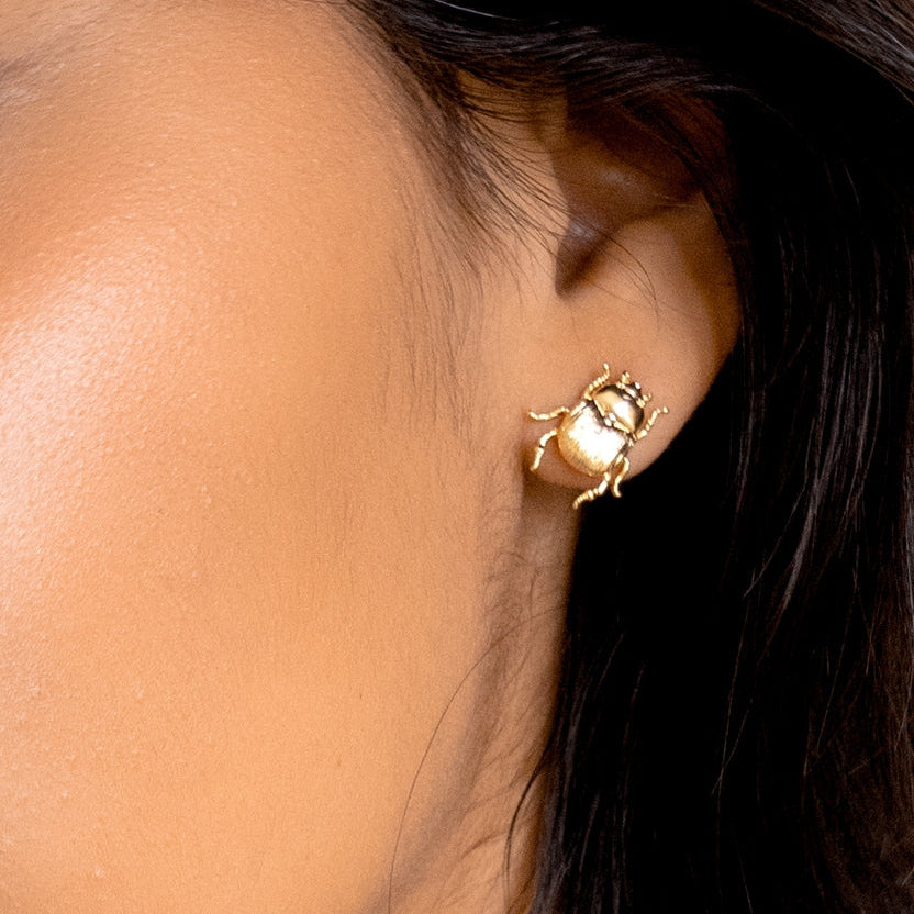 Close-up of a gold earring worn by a person with dark hair.