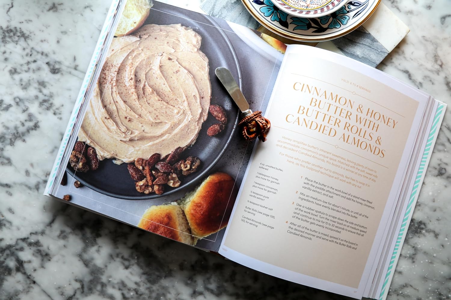 Open cookbook on a marble surface with a plate of food and text visible