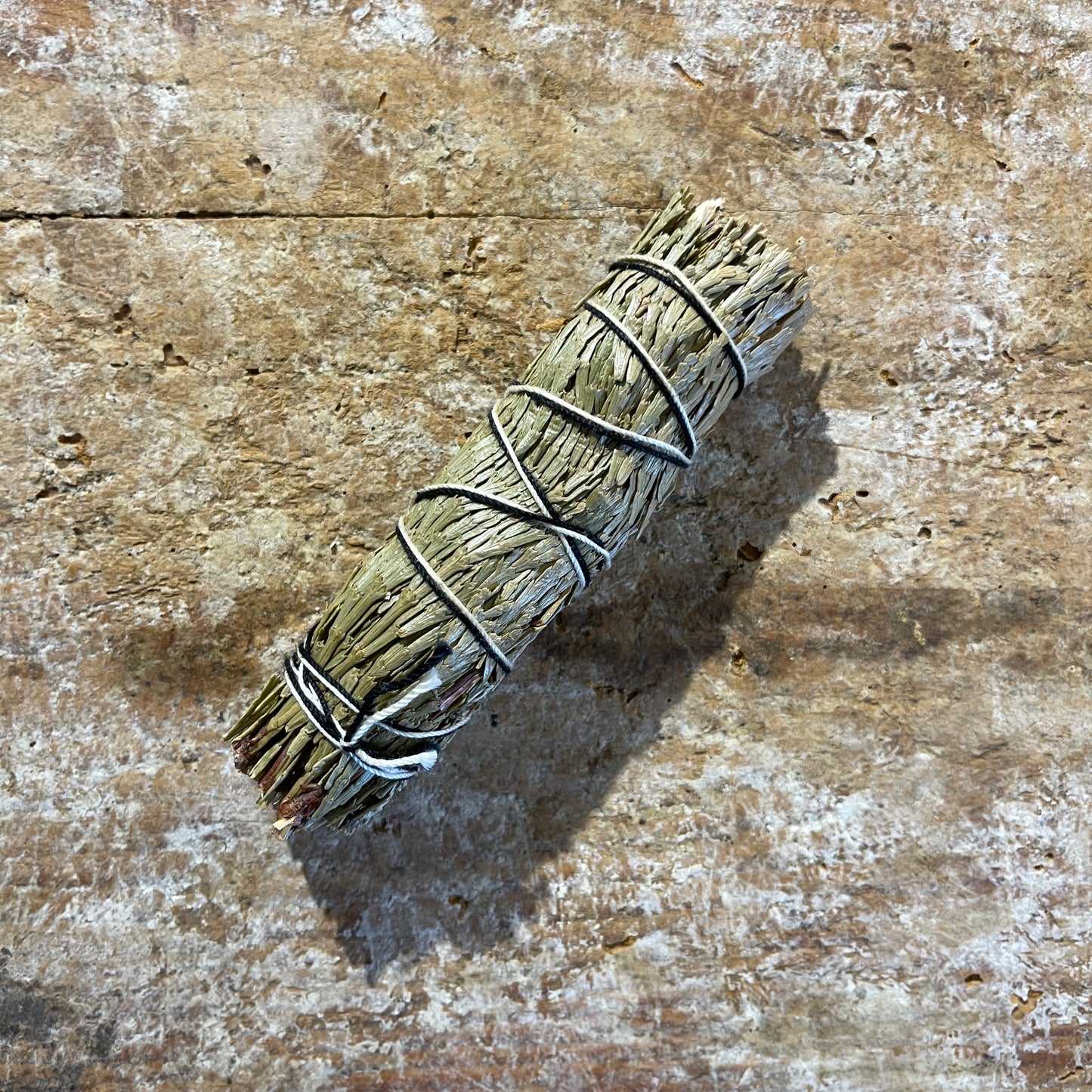 Bundled cedar and blue sage on a textured wooden surface