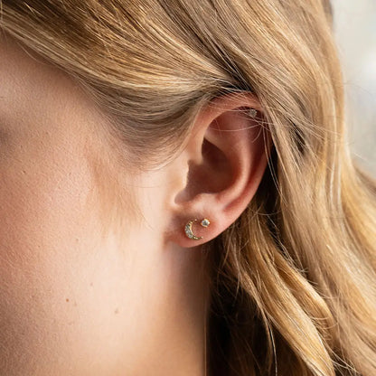 Close-up of an ear wearing a gold hoop earring with a blurred background