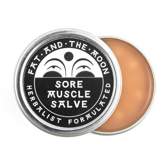 Sore muscle salve in a metal tin with a white lid on a white background