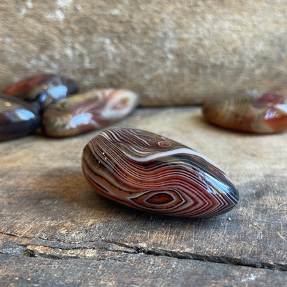 Polished carnelian stone with concentric patterns on a wooden surface