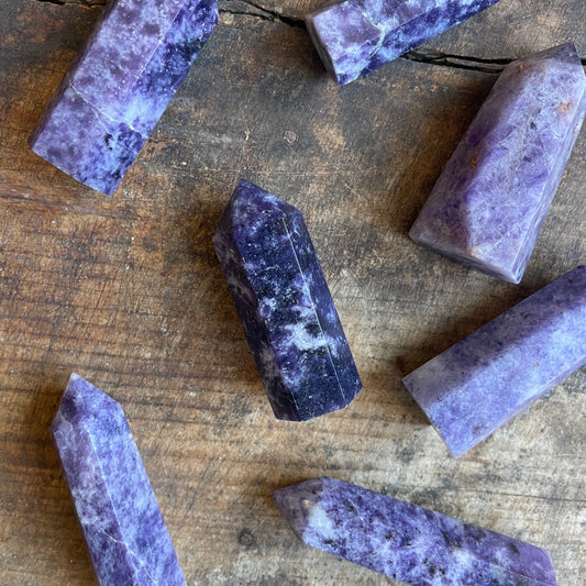 Purple and white charoite stones on a wooden surface