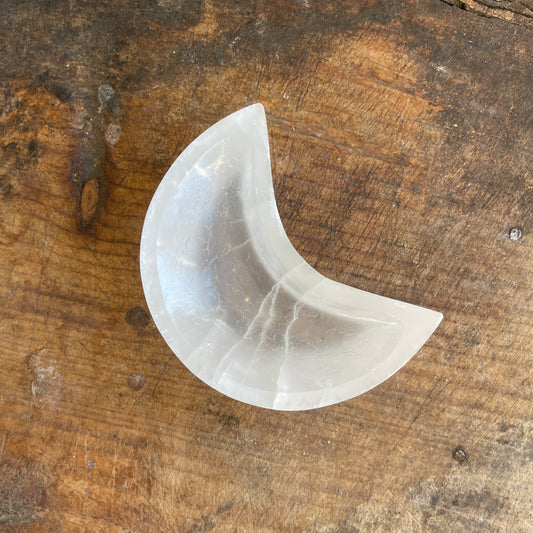 White moon shaped selenite dish on a wooden surface