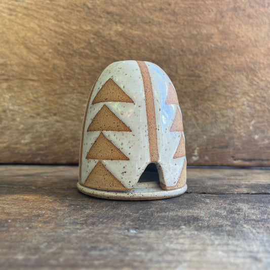 Ceramic incense hut with geometric design on a wooden surface