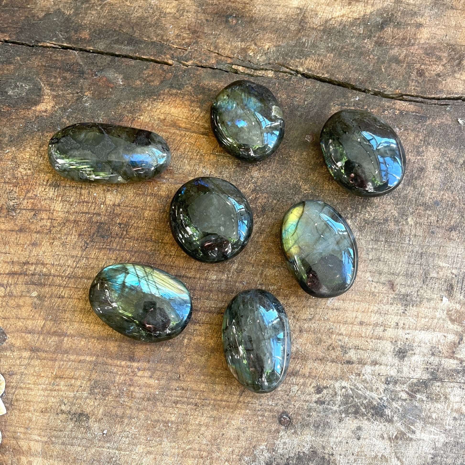 Seven labradorite stones on a wooden surface