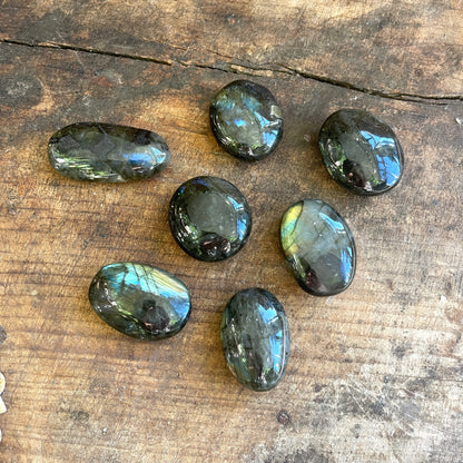 Seven labradorite stones on a wooden surface