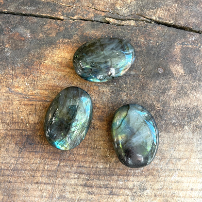 Three labradorite stones on a wooden surface