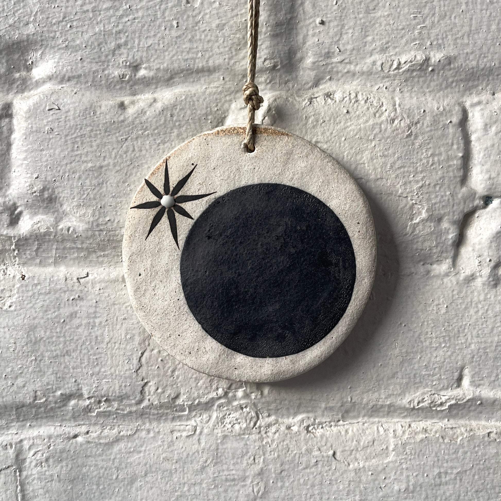 Round ceramic wall ornament with black star and moon design
