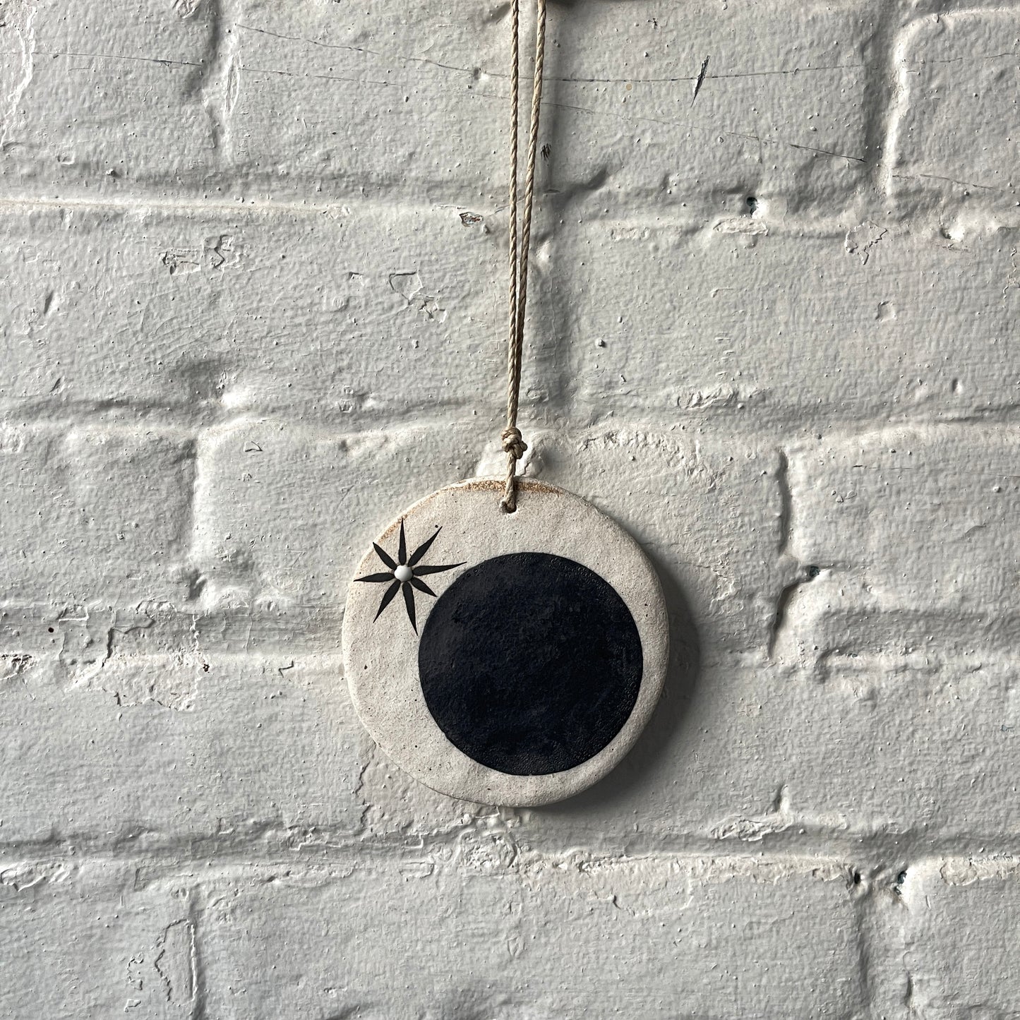 Round ceramic wall ornament with black star and moon design