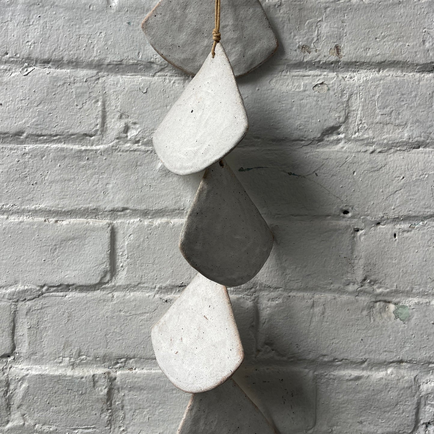 Layered White stoneware shells against a white brick wall