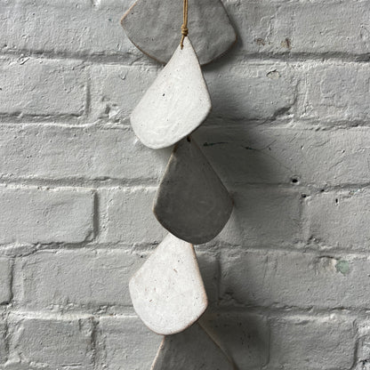 Layered White stoneware shells against a white brick wall