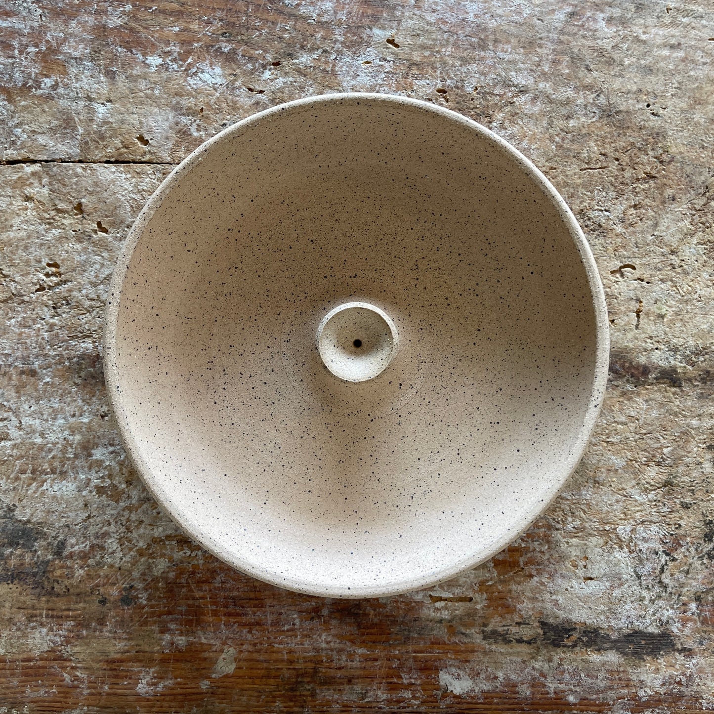 Speckled beige ceramic incense burner on a textured wooden surface