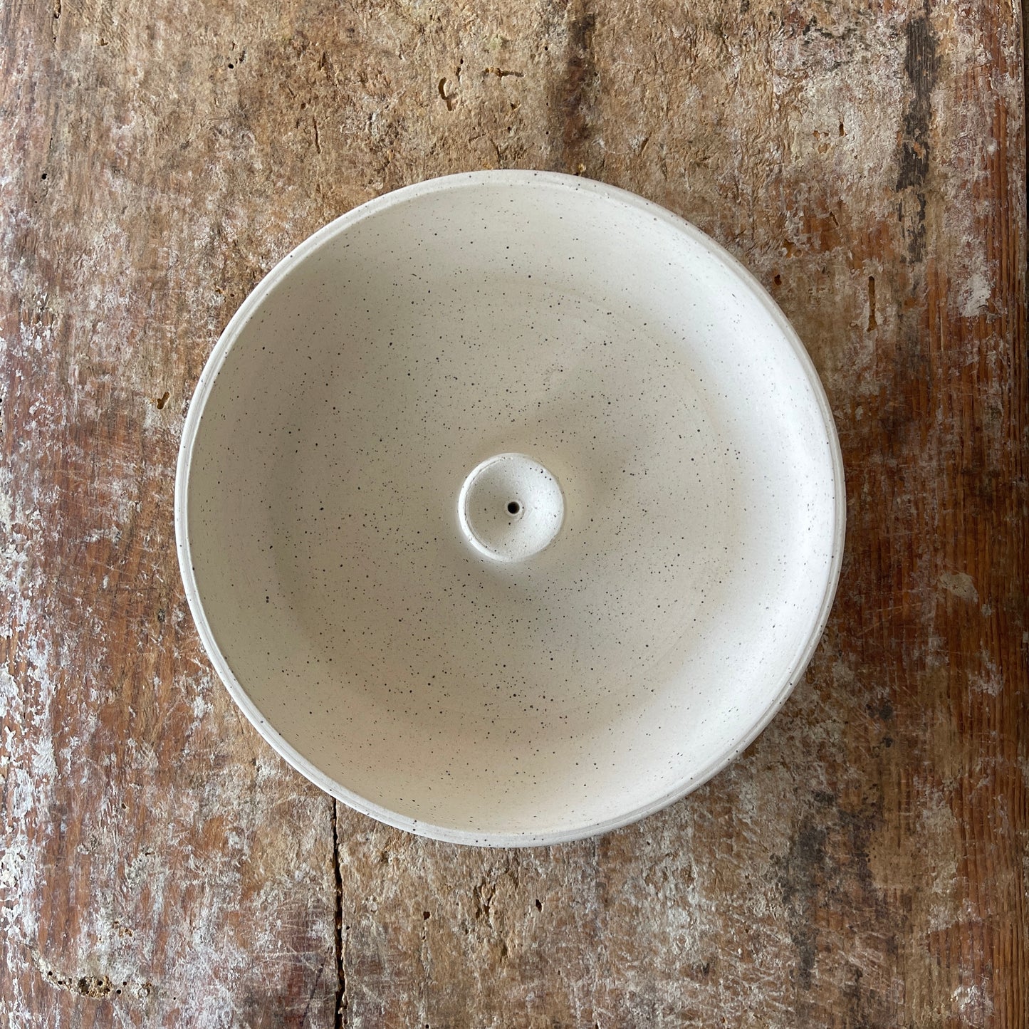 White ceramic incense burner on a rustic wooden surface