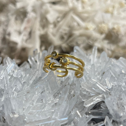 A gold ring with small clear gemstones, displayed on a bed of white crystal formations.