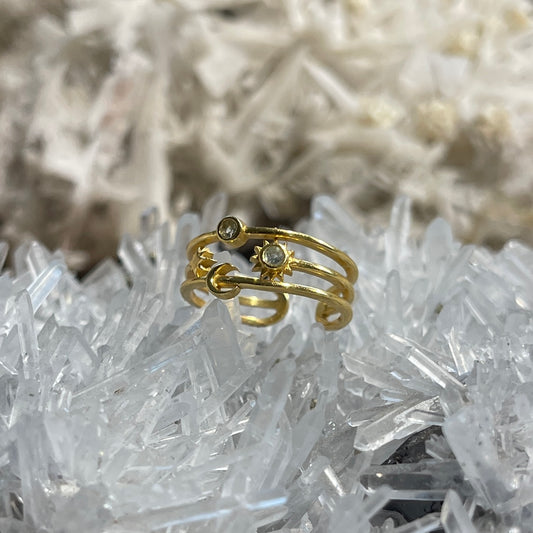 A gold ring with small clear gemstones, displayed on a bed of white crystal formations.