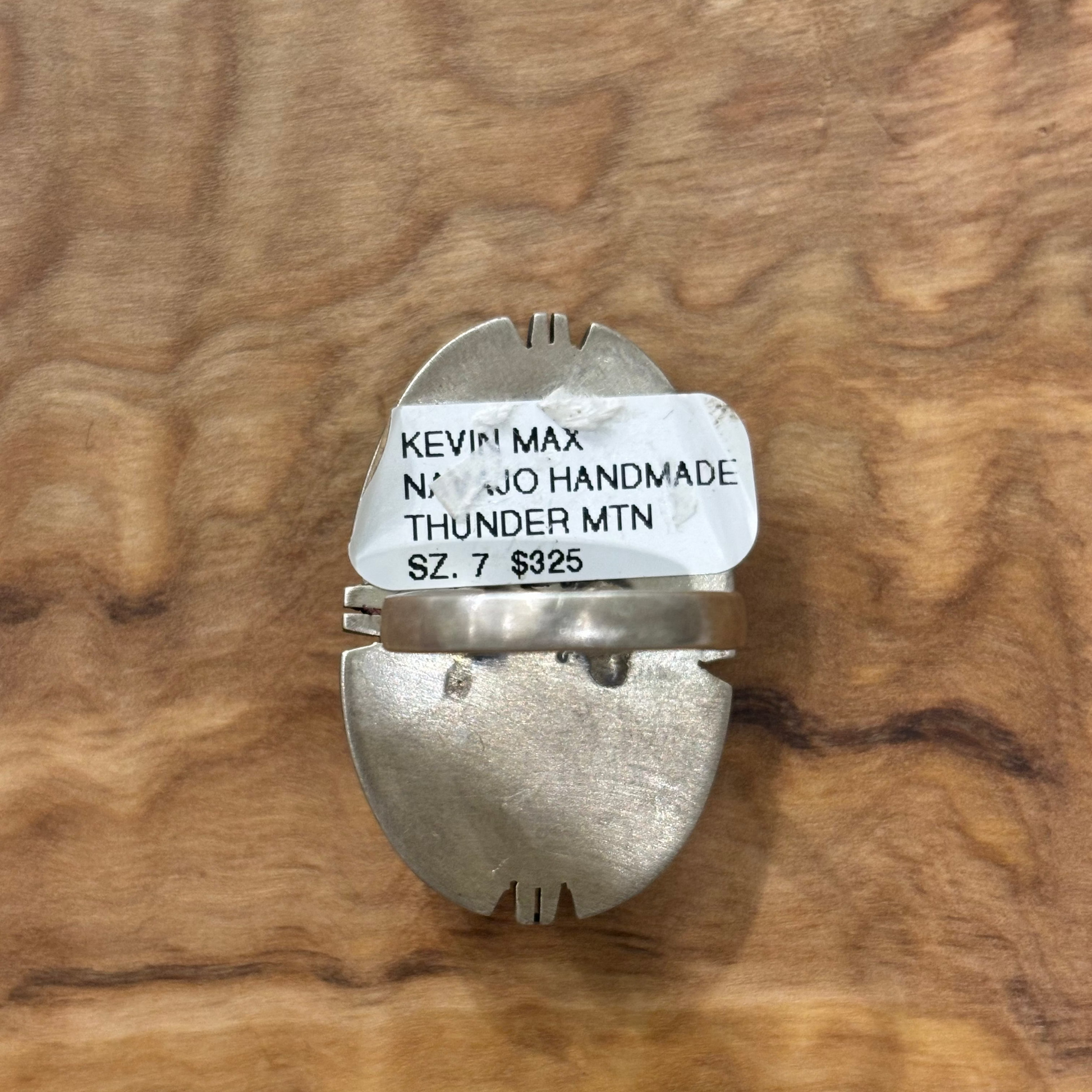 A handmade silver metal ring with a white paper label reading 'KEVIN MAX NO. 43 NAVAJO HANDMADE THUNDER MTN 