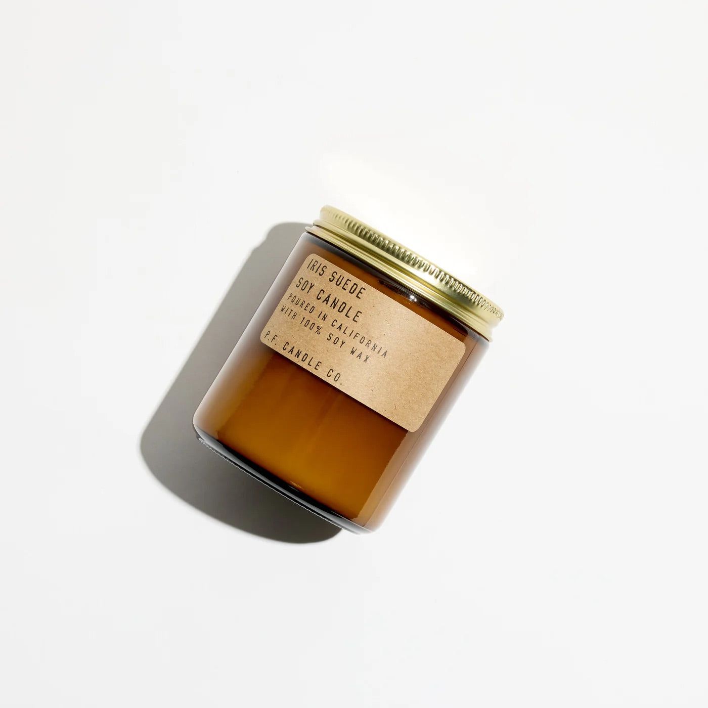 Amber glass candle with a gold lid and label on a white background