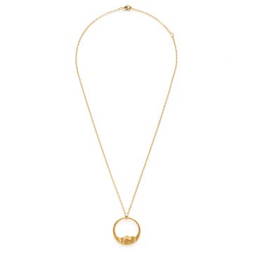 A delicate gold chain necklace featuring a small circular pendant with a tiny central figure, displayed against a solid white background.