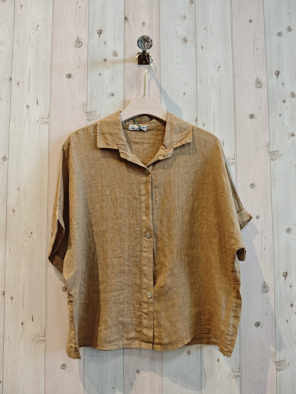 Brown shirt on a hanger against a wooden wall