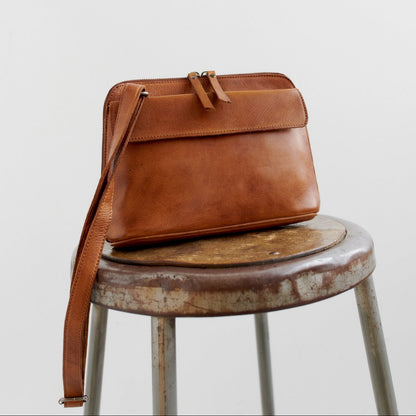 Brown leather bag on a rustic stool against a light background