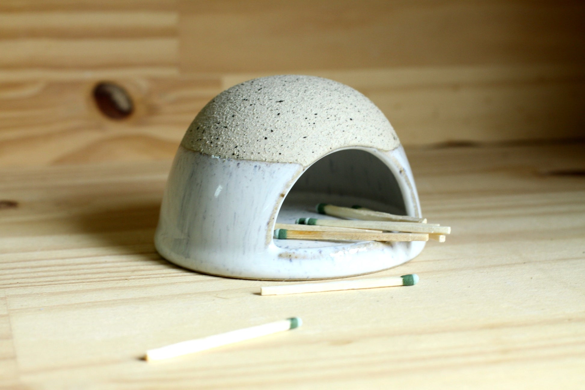 Ceramic dome-shaped match striker with matches on a wooden surface
