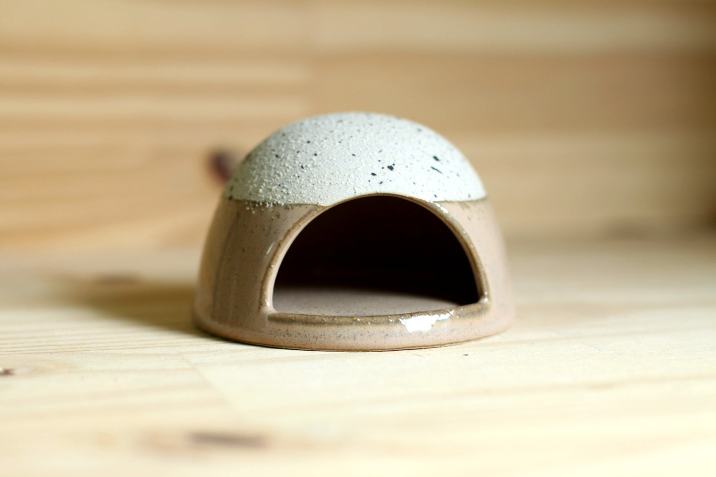 Brown ceramic dome-shaped match striker on a wooden surface