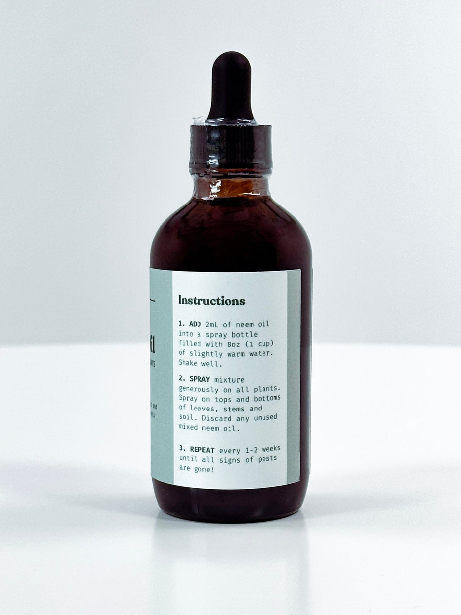 An amber glass dropper bottle with a black rubber bulb top and a white instruction label, photographed on a clean light gray background.
