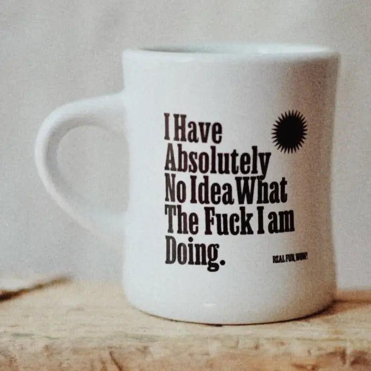 White mug with humorous text on a wooden surface
