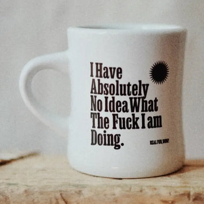 White mug with humorous text on a wooden surface