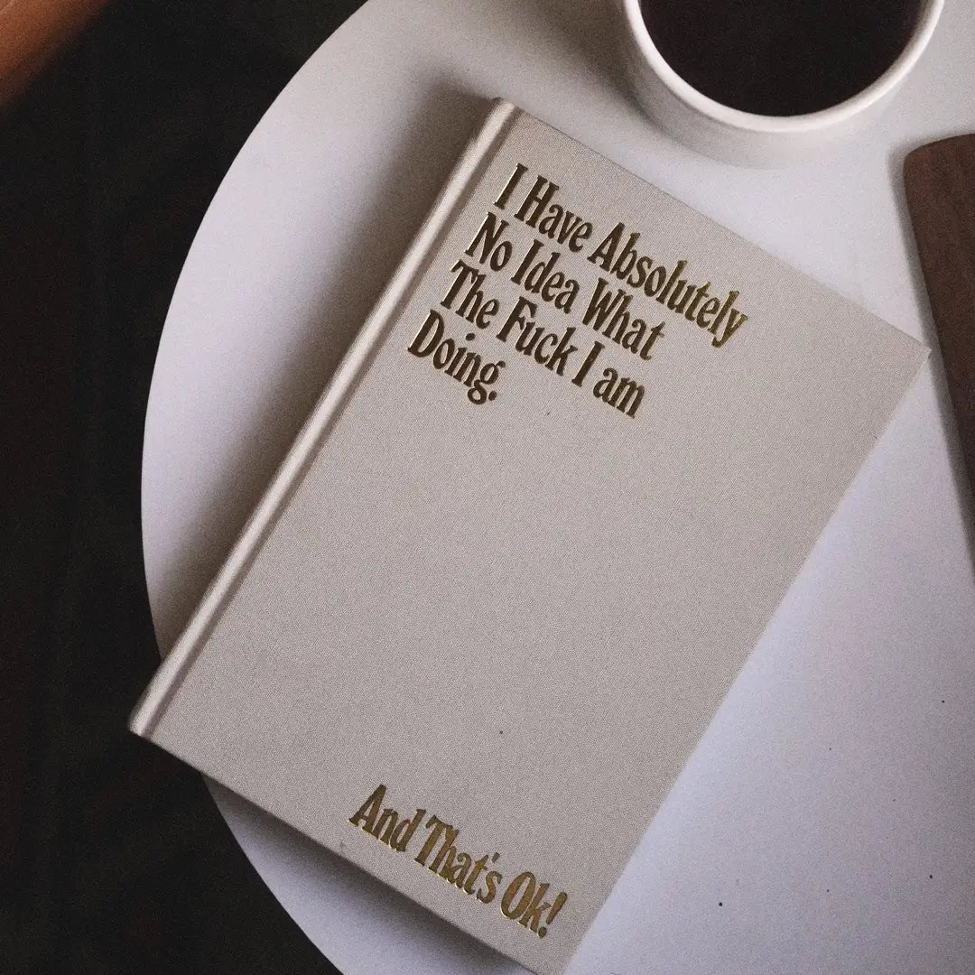 Notebook with humorous text on a white surface with a cup of coffee.