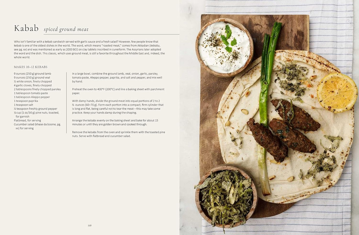 Kabab dish with flatbread, greens, and a side of yogurt on a wooden board.