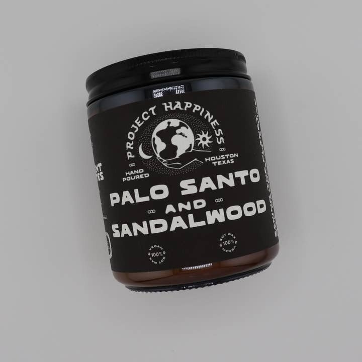 Black container labeled 'Palo Santo and Sandalwood' by 'Project Happiness' on a gray background