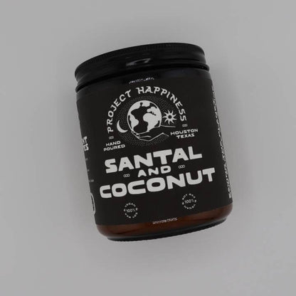Black candle jar labeled 'Project Happiness' with 'Santal and Coconut' on a gray background