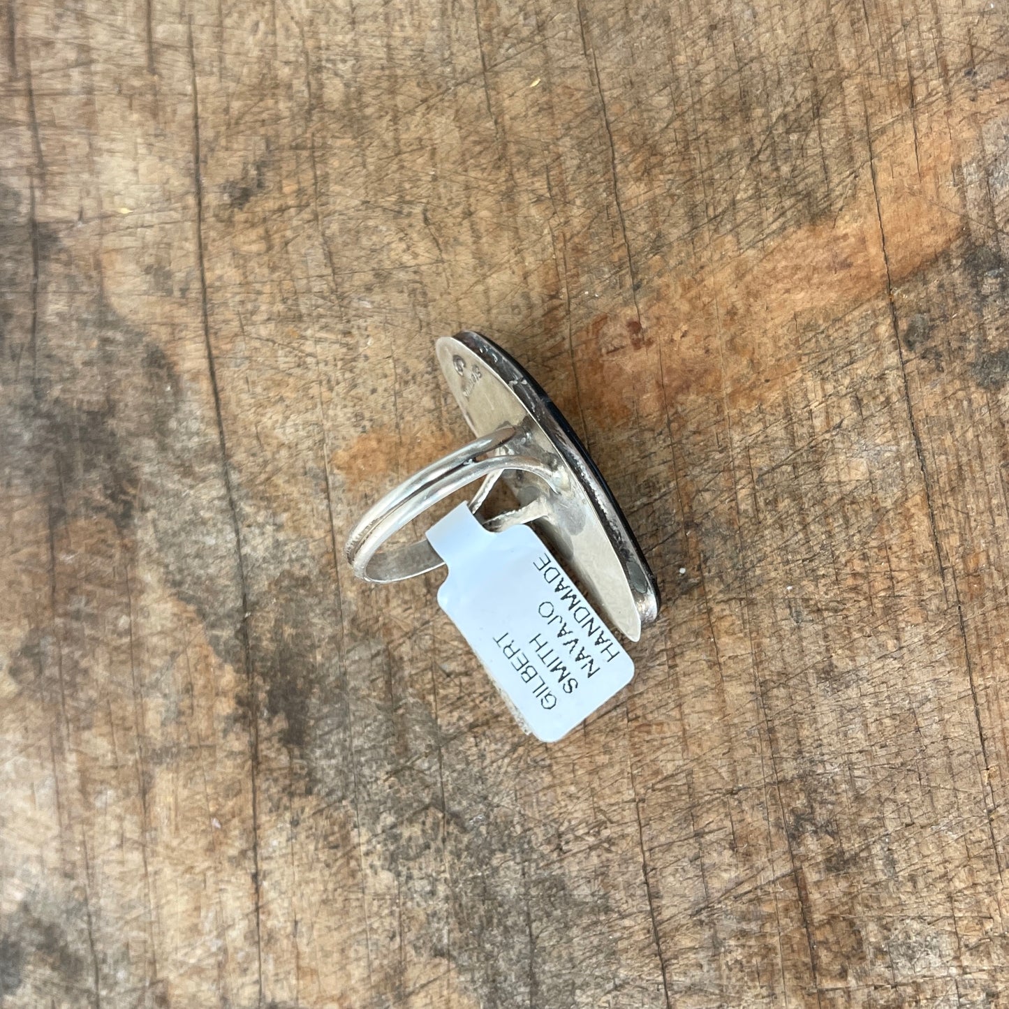 Silver ring with a tag on a wooden surface